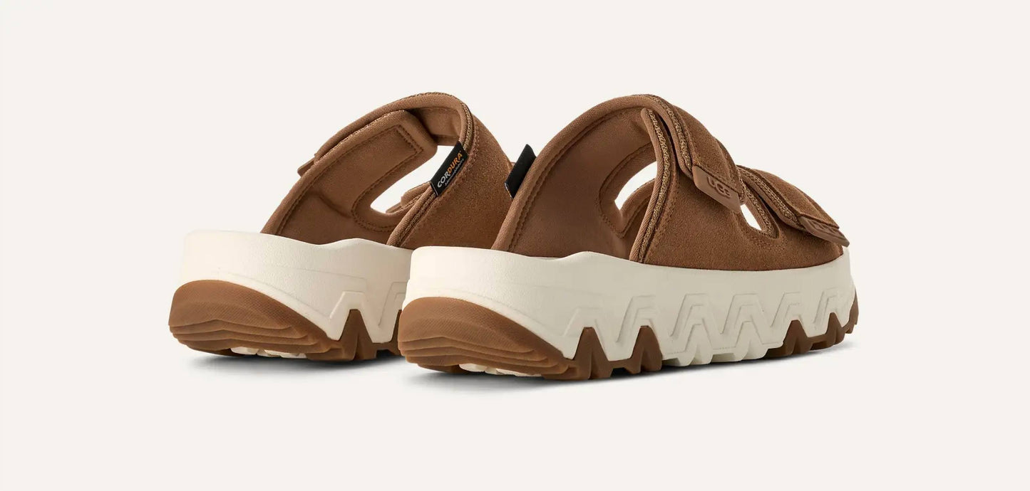 Ugg - महिलाओं के लिए कैपिटल स्ट्रैप स्लाइड सैंडल