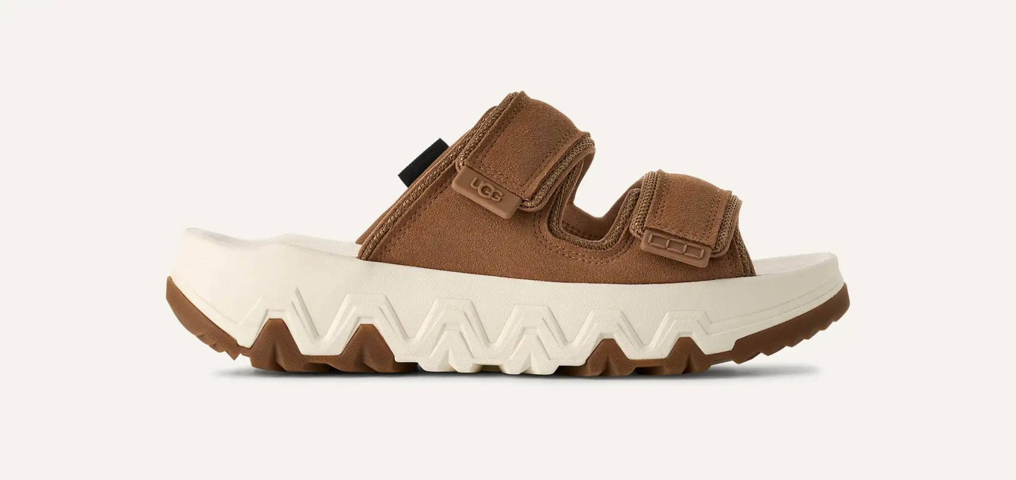 Ugg - महिलाओं के लिए कैपिटल स्ट्रैप स्लाइड सैंडल