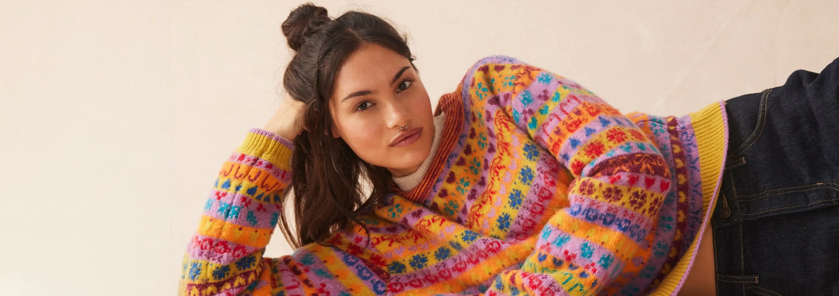 Woman wearing a colorful patterned sweater against a plain background